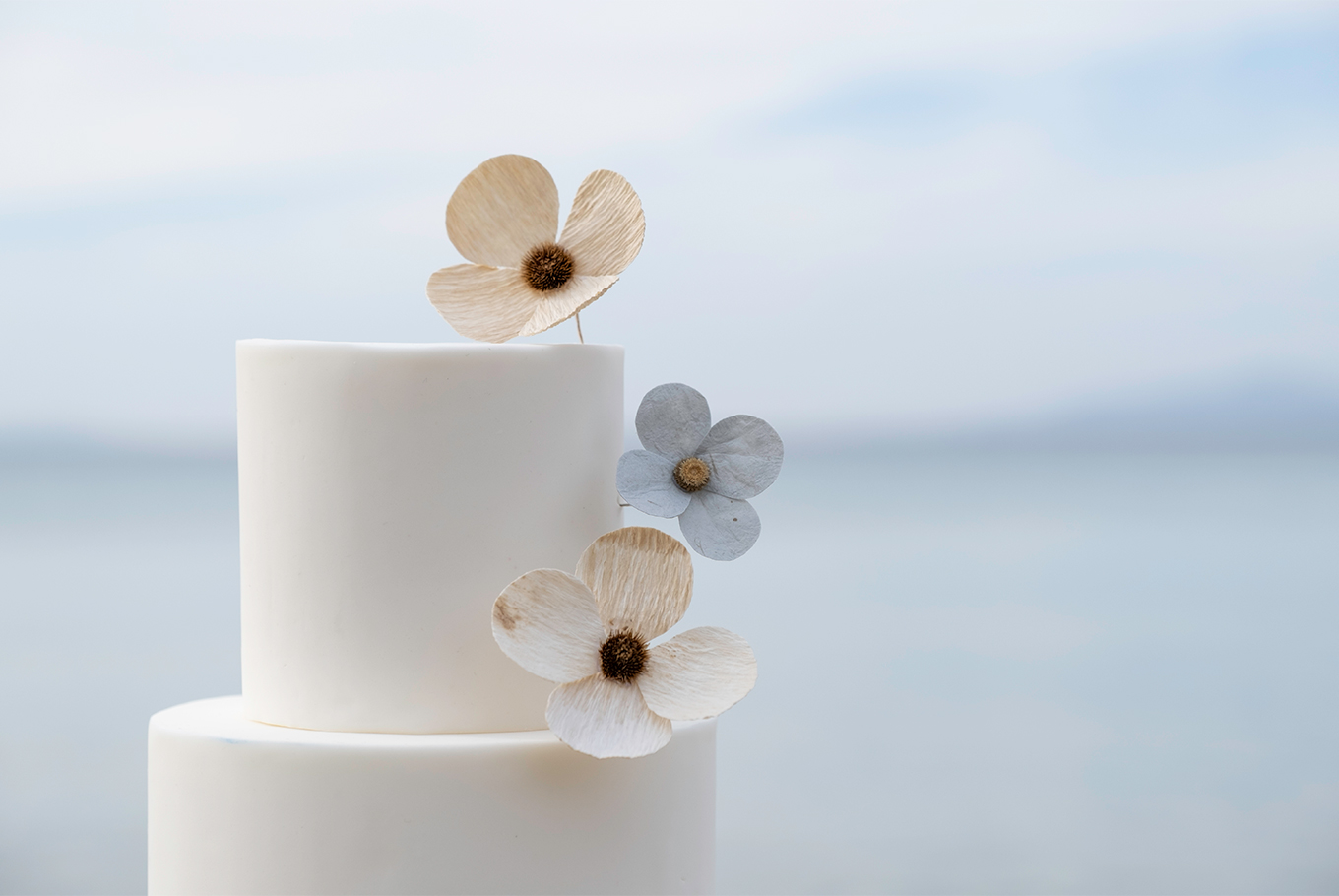 Détail décoration florale en papier blanc et bleu pastel sur gateau étages créé par Étoile Vagabonde