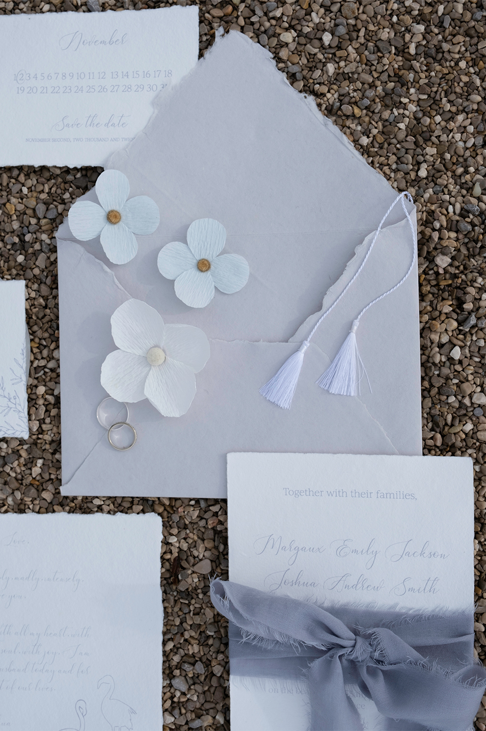 Fleurs en papier posées sur set de papeterie faire part de mariage. Création : Étoile Vagabonde